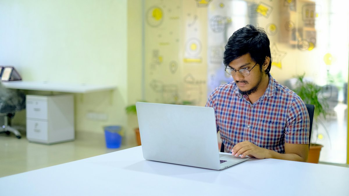 A student working at a laptop in a bright studio