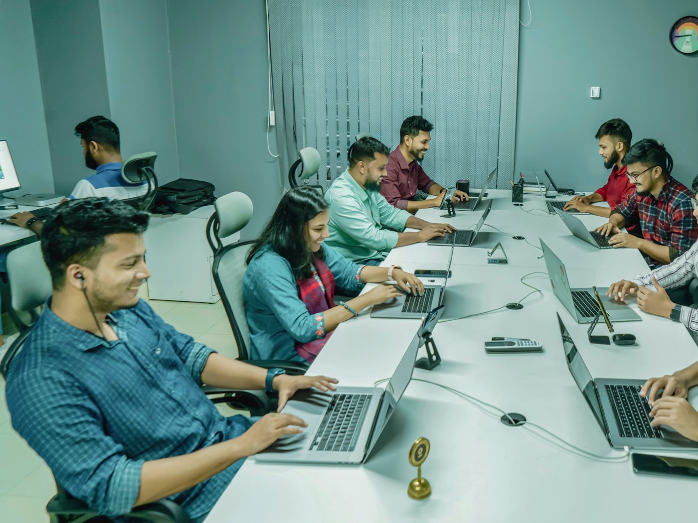 A young team working along both sides of a long desk, laptops open